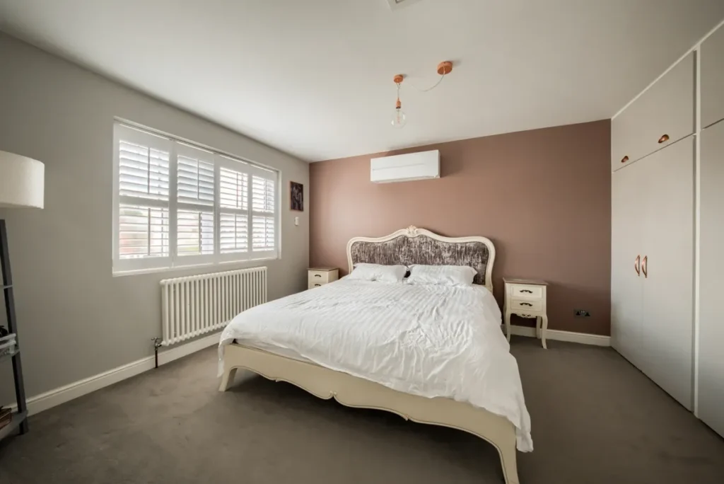 dusky pink bedroom with a 2.5 kilowatt air conditioner mounted above the bed
